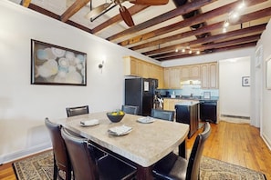 A dining area with a table and chairs, a kitchen with cabinets and appliances, and a ceiling with exposed beams. - Charming loft near City Market with washer/dryer, AC - walk to river (Savannah)