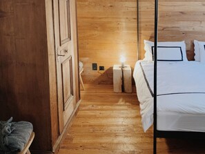 Ein Zimmer mit Holzwänden, einem Bett, einem Nachttisch und einem Beistelltisch.