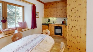 Una cucina accogliente con mobili in legno, un tavolo da pranzo con un runner in pizzo e una finestra vista alberi.