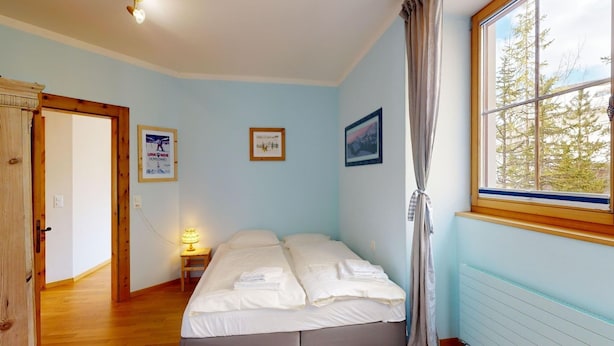 Una camera da letto con un letto, una finestra con tende e un pavimento in legno.