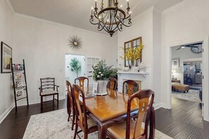 A dining room with a wooden table, six chairs, a chandelier, and a floral arrangement. - Charming Victorian home with modern comforts & steps from parks (Savannah)