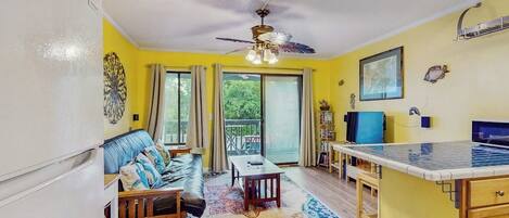 A compact living space with a sofa, a dining table, a kitchen area, and a ceiling fan.