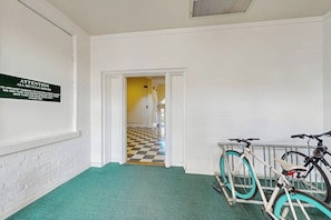 A hallway with a sign on the wall, a checkered floor, and bicycles parked against the wall. - Charming, historic condo w/ a full kitchen, free WiFi, & central A/C (Savannah)