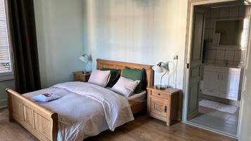 Une chambre à coucher avec un lit en bois, des tables de chevet, une commode et une vue sur la salle de bain.