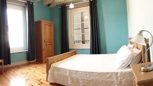 Quarto com cama, guarda-roupa de madeira e janela com cortinas.