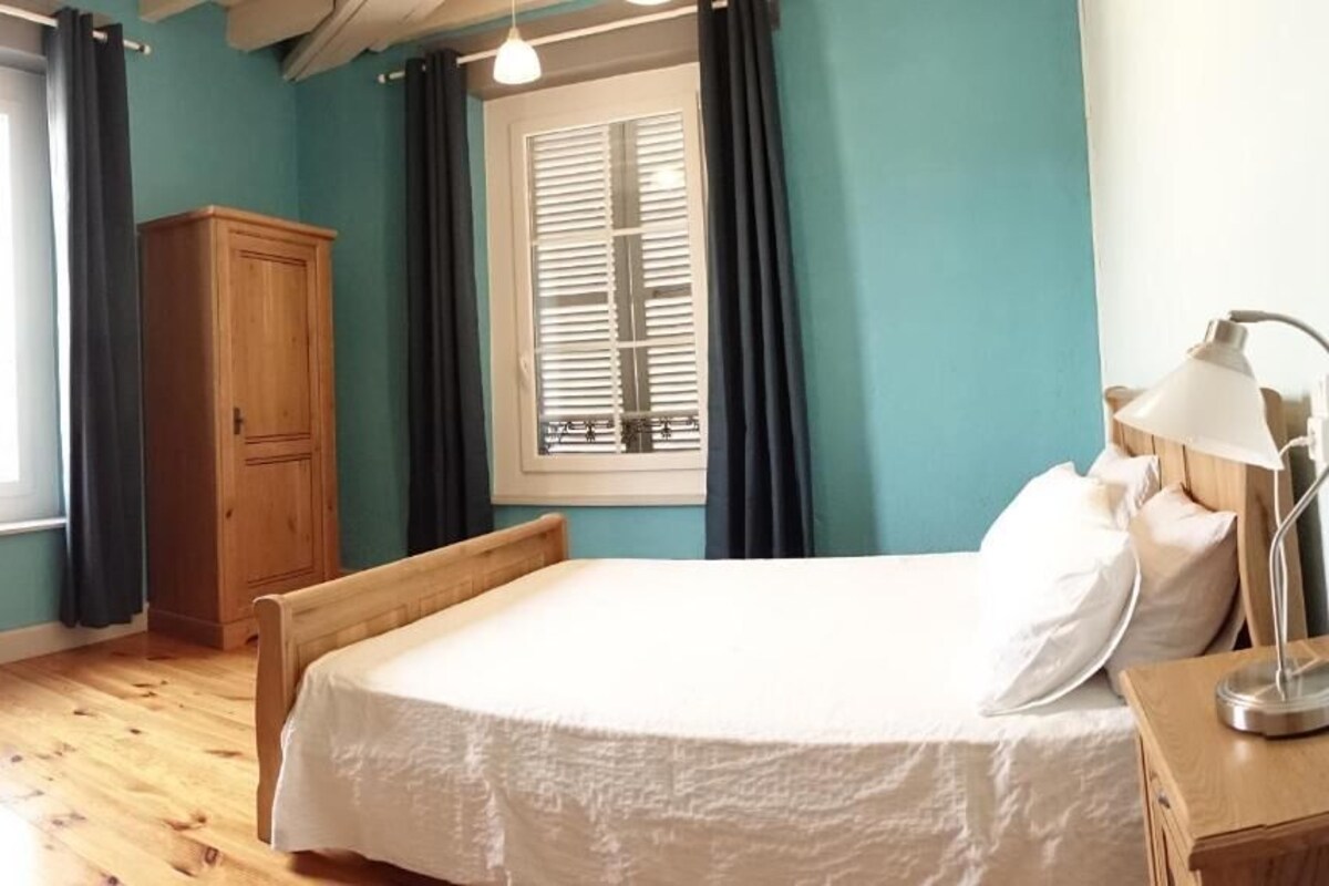 A room with a bed, wooden wardrobe, and a window with curtains.
