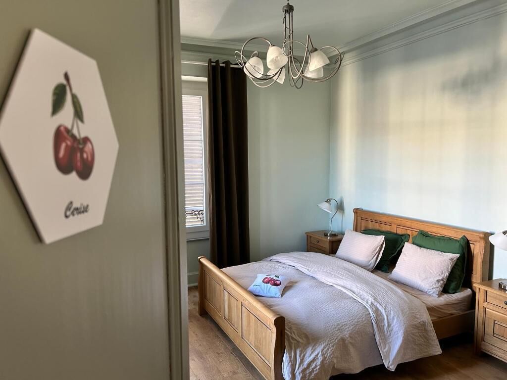 A bedroom with a wooden bed, a nightstand, a lamp, and a window with curtains.
