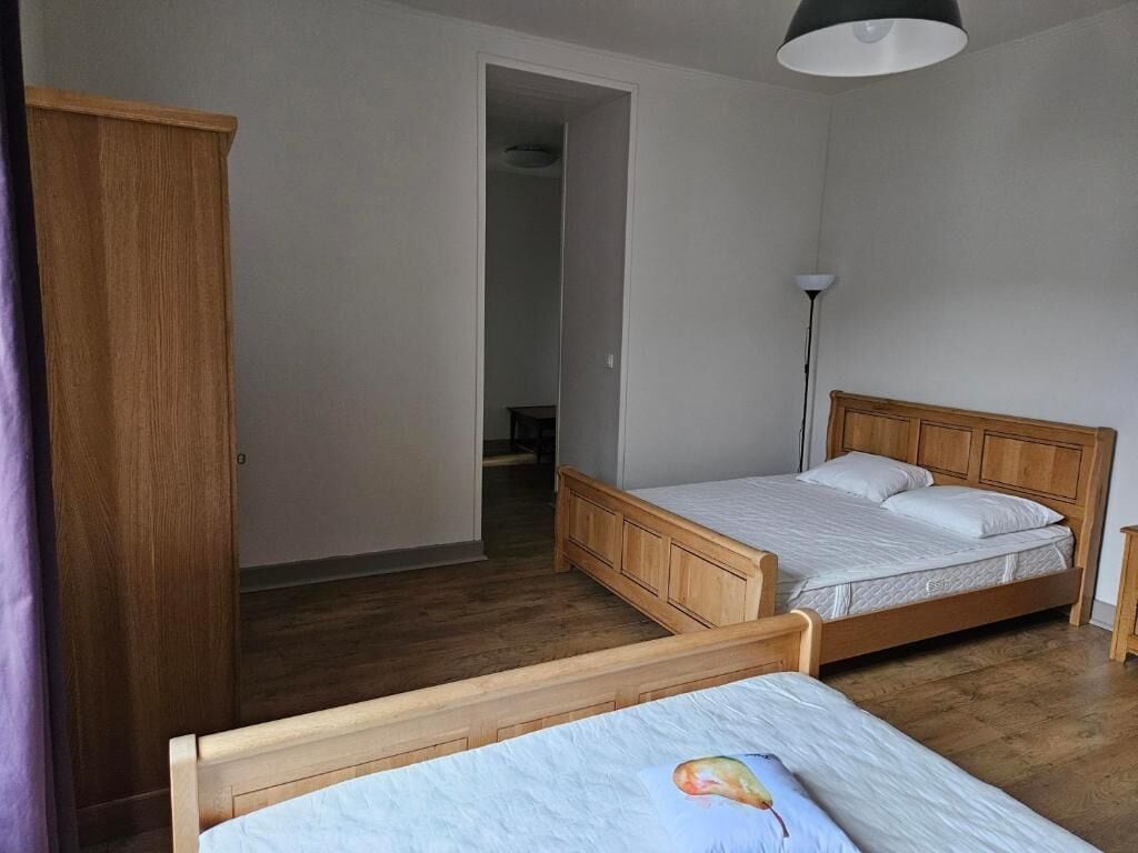 A bedroom with two wooden beds, a wardrobe, and a door leading to another room.