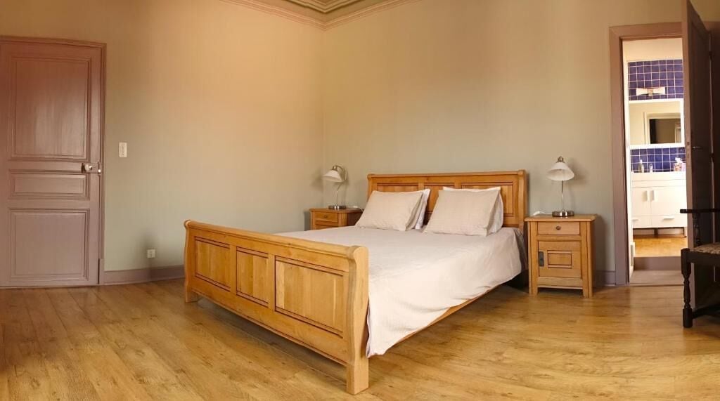 Een slaapkamer met een houten bed, nachtkastjes en een deur.