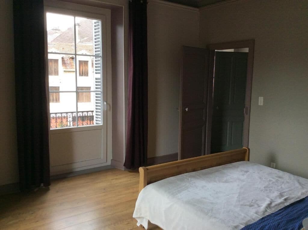 Un dormitorio con cama de madera, una puerta y una ventana con cortinas.