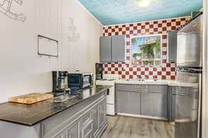 A kitchen with a checkered backsplash, a microwave, a stove, and a refrigerator. - Cozy coastal escape near the beach & shopping with fast WiFi, AC (Tybee Island)