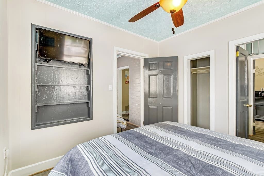 Ein Schlafzimmer mit einem Bett, einem Deckenventilator, einem Fenster und einer Tür.