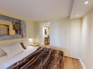 Un dormitorio con cama, mesita de noche, un cuadro en la pared y un armario.