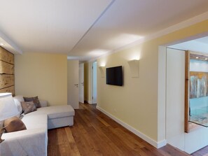 Una sala de estar moderna con un sofá, un televisor montado en la pared y piso de madera.
