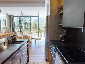 Eine moderne Küche mit großem Fenster, Holzboden und einem Essbereich mit weißen Stühlen.