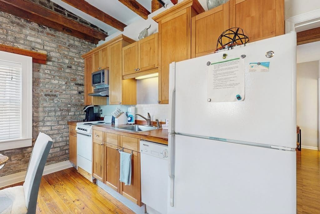 Une cuisine avec des meubles de rangement en bois, un réfrigérateur blanc, une cuisinière et un four à micro-ondes.