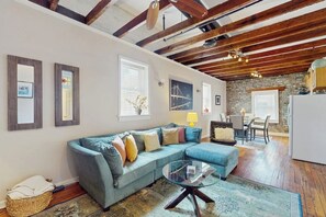 A living room with a sectional sofa, a glass coffee table, and a dining area with a table and chairs. - Stunning City Market condo with W/D - walk to shops & dining (Savannah)