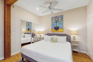 A bedroom with a bed, bedside tables, a ceiling fan, and a painting on the wall. - Stunning City Market condo with W/D - walk to shops & dining (Savannah)