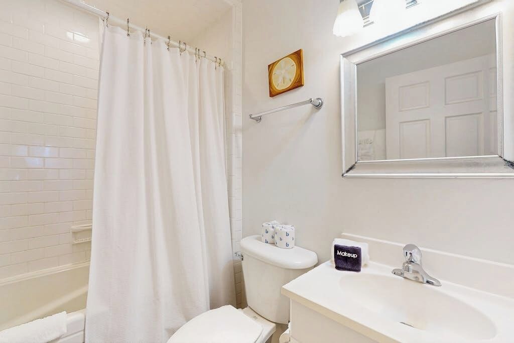 Un baño con una bañera blanca, un inodoro y un lavamanos con espejo.