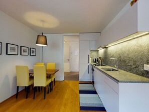 A modern kitchen with a granite countertop, a built-in sink, and a dining area with yellow chairs and a table. - Apartment Belvair 3 by Interhome (Zuoz)