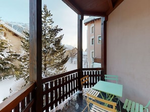 Un balcon avec une balustrade en bois, une table et une chaise.