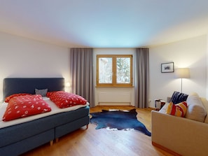 Une chambre à coucher avec un lit, un canapé, une fenêtre et une lampe.