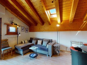 A cozy living room with a wooden ceiling, a sofa, a coffee table, and a floor lamp. - Apartment Polaschin B12 by Interhome (Sils Maria)