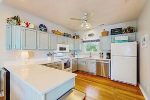 A kitchen with white cabinets, a microwave, a refrigerator, and a ceiling fan. - Seaside serenity home with beach access, washer/dryer, & dog-friendly (Tybee Island)