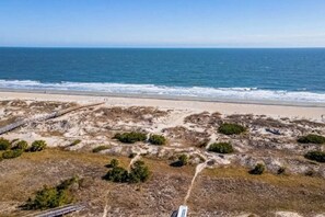 A coastal landscape with a sandy beach, a dirt path, and sparse vegetation. - Seaside serenity home with beach access, washer/dryer, & dog-friendly (Tybee Island)
