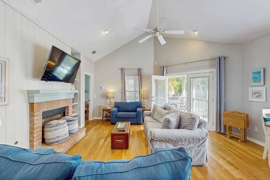 A living room with a fireplace, sofas, a television, and a ceiling fan.