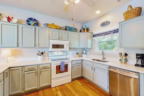 A kitchen with white cabinets, a microwave, an oven, a sink, and a dishwasher. - Seaside serenity home with beach access, washer/dryer, & dog-friendly (Tybee Island)