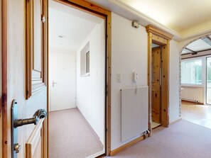 A hallway with a wooden door, a radiator, and a view of a balcony. - Apartment Ova Cotschna 301 by Interhome (St. Moritz)