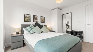 A modern bedroom with a bed, bedside tables, a mirror, and artwork on the wall. - Central Liverpool 2 Bedroom Apartment, Large, Modern, WIFI, Sleeps 4 (Liverpool)