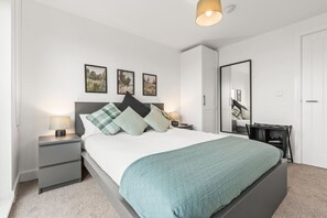 Ein modernes Schlafzimmer mit einem Bett, Nachttischen, einem Spiegel und Kunstwerken an der Wand.