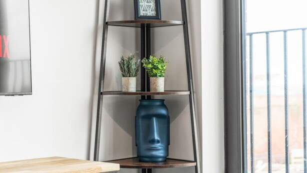 A corner of a room with a wooden table, a blue vase, and a metal shelf with plants. - Central Liverpool 2 Bedroom Apartment, Large, Modern, WIFI, Sleeps 4 (Liverpool)