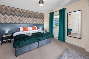 A bedroom with a bed, a nightstand, a mirror, and a view of the outdoors. - Hot Tub 3BR Flat Near Snowdon | Parking | Sleeps 6 (Penmorfa)