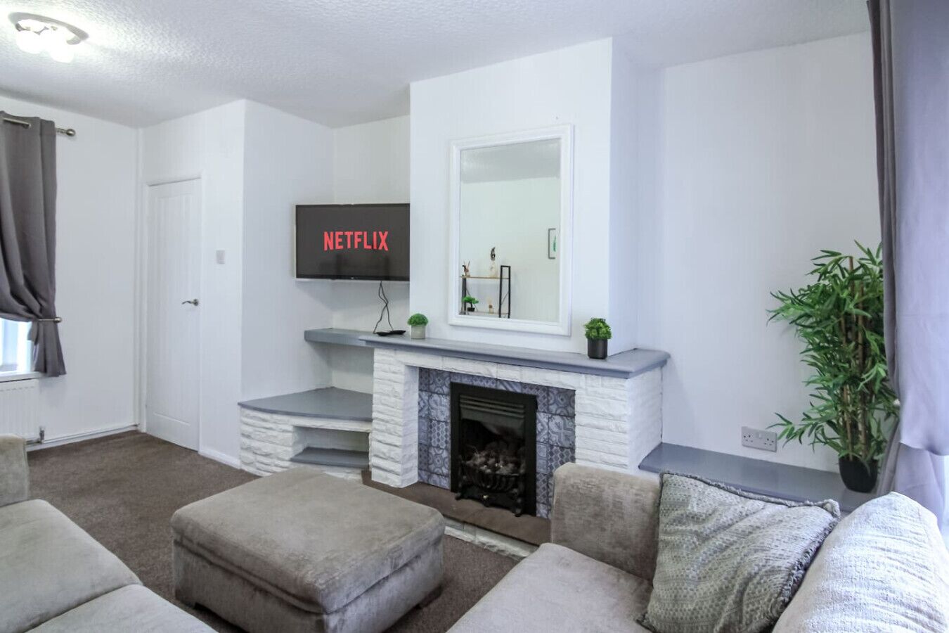 A living room with a fireplace, a flat-screen TV mounted above it, and a sofa.
