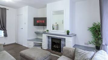 A living room with a fireplace, a flat-screen TV mounted above it, and a sofa.