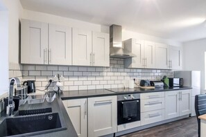 A modern kitchen with white cabinets, a black countertop, and a built-in oven. - Modern 2BR Apartment, S1 City Centre, WIFI, Sleeps 6 (Greater Manchester)