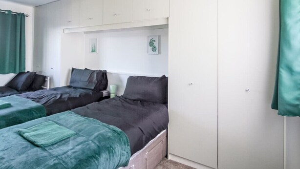 A room with two beds, a wardrobe, and a small table. - Modern 2BR Apartment, S1 City Centre, WIFI, Sleeps 6 (Greater Manchester)