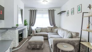 A living room with a fireplace, a sofa, an ottoman, a round table, and a bookshelf. - Modern 2BR Apartment, S1 City Centre, WIFI, Sleeps 6 (Greater Manchester)