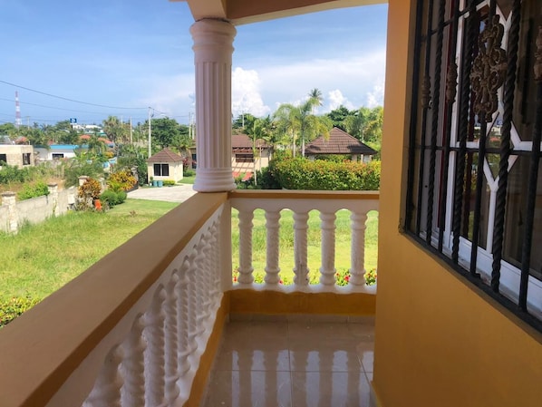A balcony with a white balustrade, a view of a residential area, and a clear sky.