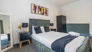 Ein modernes Schlafzimmer mit einem großen Bett, Nachttischen, einem Kleiderschrank und abstrakter Wandkunst.