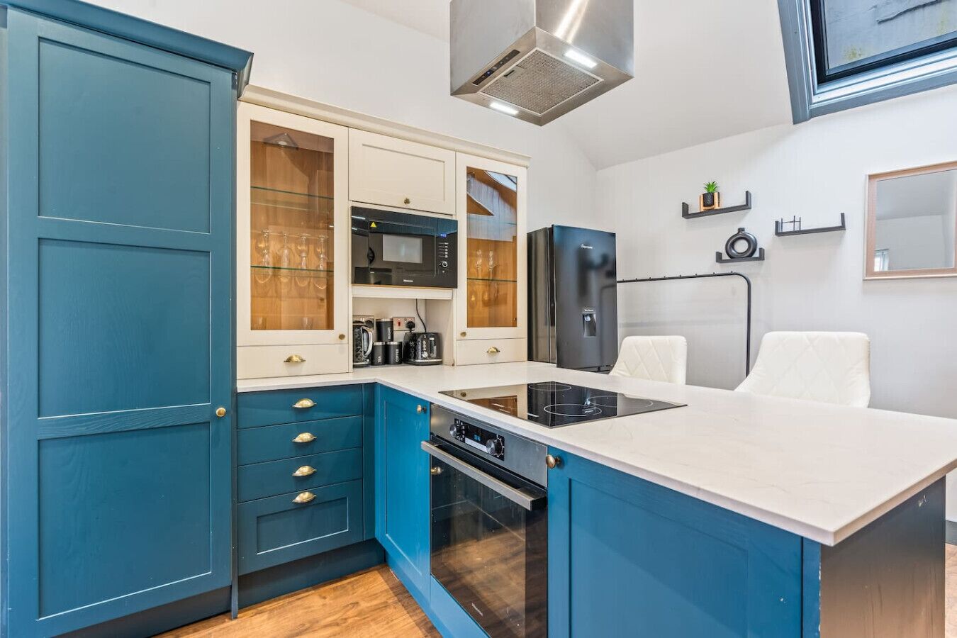 A compact kitchen with a built-in microwave, oven, and a black induction cooktop.