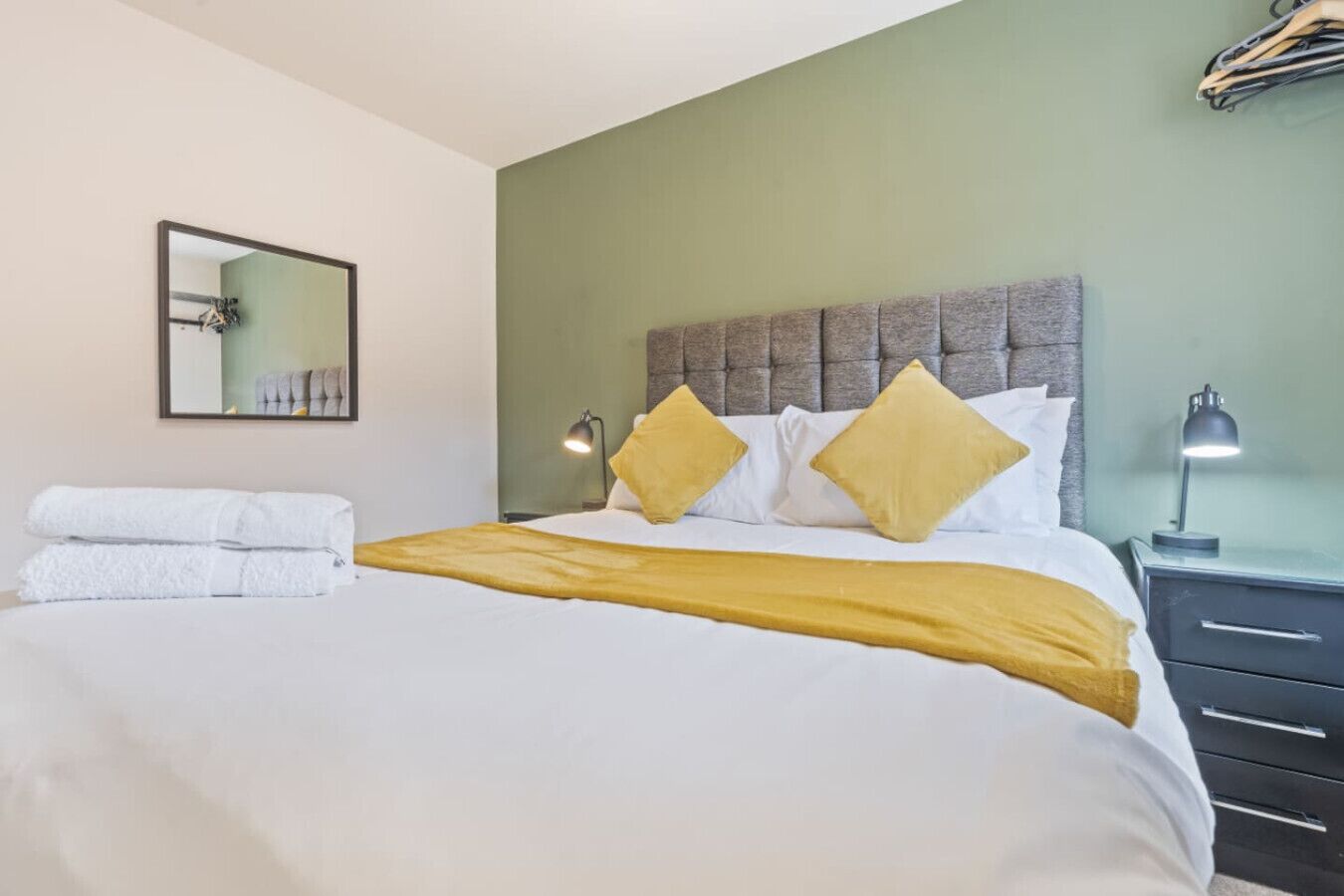 Quarto de hotel com uma cama, duas luminárias de cabeceira, uma mesa de cabeceira e um espelho na parede.