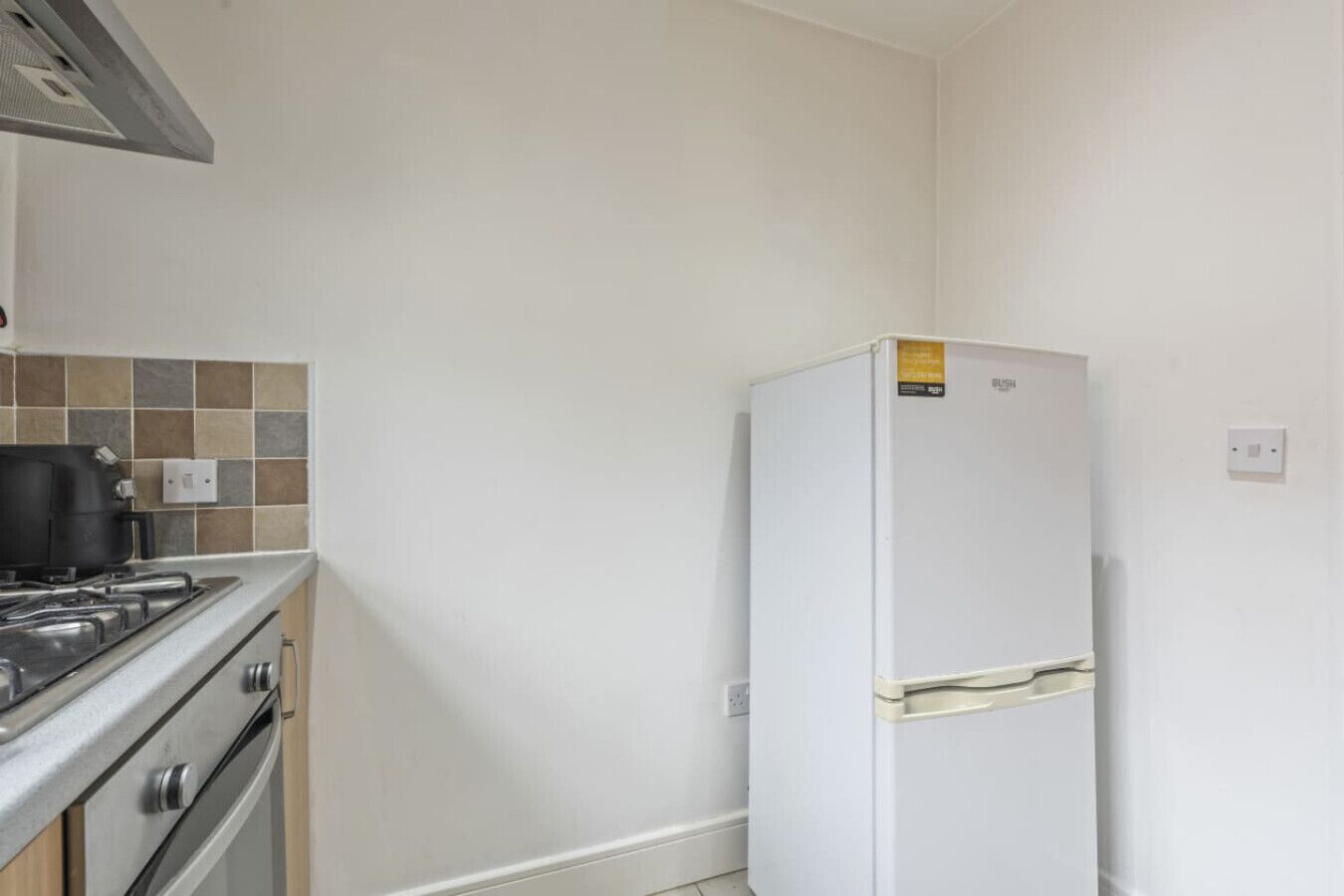 A kitchen with a stove, oven, and a white refrigerator.