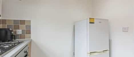 A kitchen with a stove, oven, and a white refrigerator.