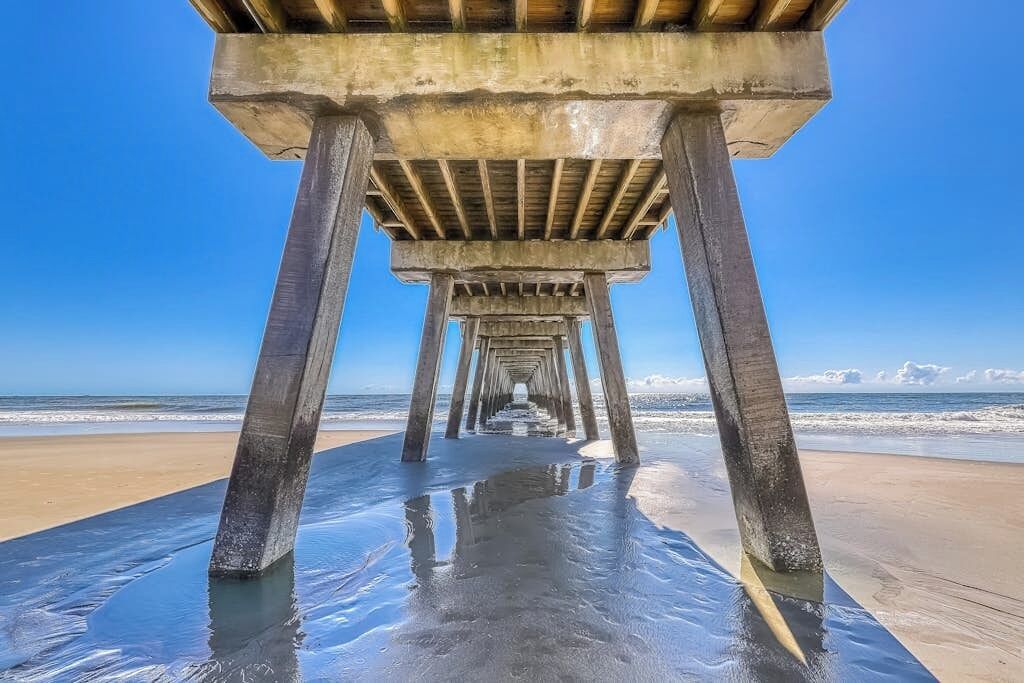Une structure de jetée en béton offrant une vue dégagée sur l’océan et la plage en arrière-plan.