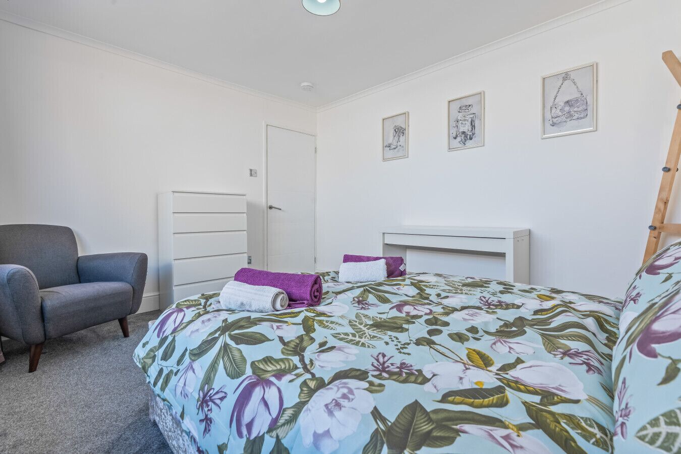 Una camera da letto con un letto, una sedia, una cassettiera e una scrivania.