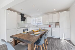 Eine moderne Küche mit weißen Schränken, einem Holztisch und einem eingebauten Backofen.
